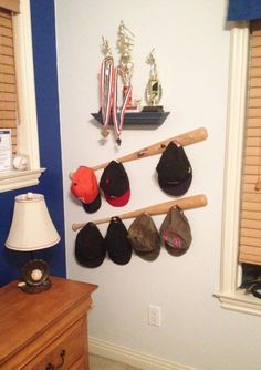 there is a hat rack with baseball caps and bats hanging on it's wall