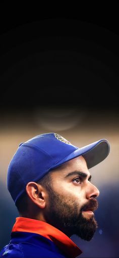 a baseball player wearing a blue hat and looking off to the side with his head tilted