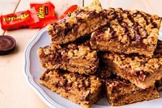 a white plate topped with granola bars next to chocolate chips and a candy bar