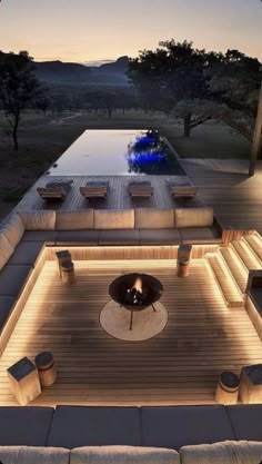 an outdoor living area with couches, tables and lights on the side of it