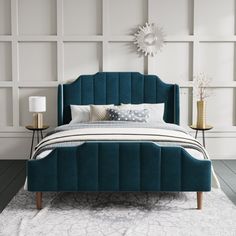 a bed with blue upholstered headboard and foot board in a white room