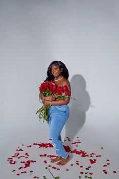 a woman holding roses in her hands and standing on the ground with petals scattered around her