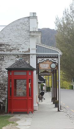 a red phone booth sitting on the side of a road