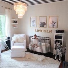 a baby in a crib next to a white chair and zebra toy on the floor