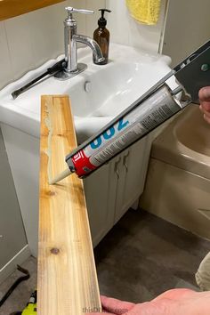 a person is using a paint roller to fix a wooden counter top in a bathroom