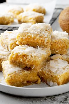 a white plate topped with coconut bars covered in icing