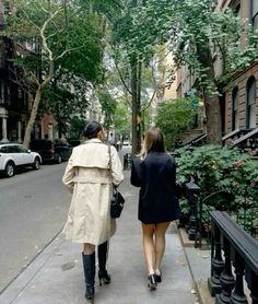 two people walking down the sidewalk in an urban area