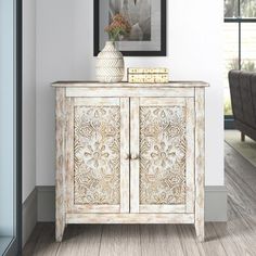 a white cabinet sitting in a living room next to a couch and table with a vase on top of it