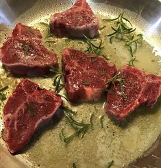 four pieces of raw meat sitting on top of a metal pan covered in seasoning