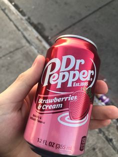 a person holding up a pink soda with strawberries and cream