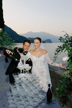 a bride and groom standing next to each other with champagne glasses in front of them