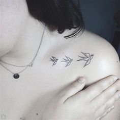 a woman's chest with three small birds on the left side of her shoulder