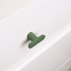 a green handle on a white cabinet in a room