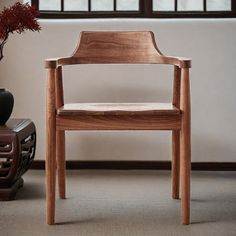 a wooden chair sitting in front of a window next to a vase with red flowers