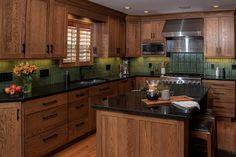 a large kitchen with wooden cabinets and black counter tops, along with green tile backsplash