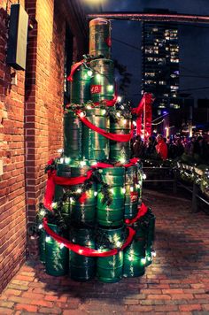 a christmas tree made out of cans with lights on it in the middle of a brick walkway