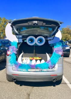 the trunk of a car decorated with blue and purple feathers, eyes and tailings