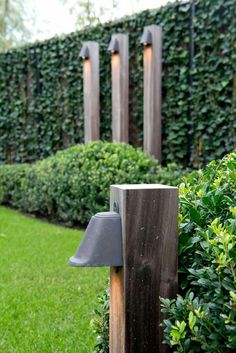 a wooden post with a light on it next to some bushes