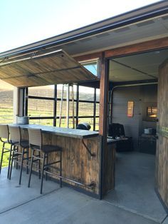 an outdoor bar with stools and barstools in front of the open door