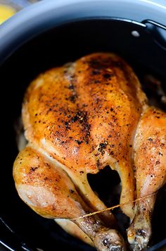 a whole chicken in a slow cooker with lemons and seasoning on the side