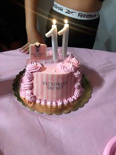 a pink birthday cake with two candles on it