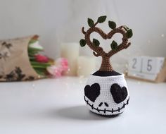 a crocheted skull planter sitting on top of a table next to candles