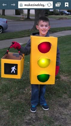 a young boy dressed as a traffic light holding a box with a walk signal on it