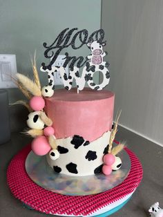 a pink and black cake sitting on top of a table next to a toy cow