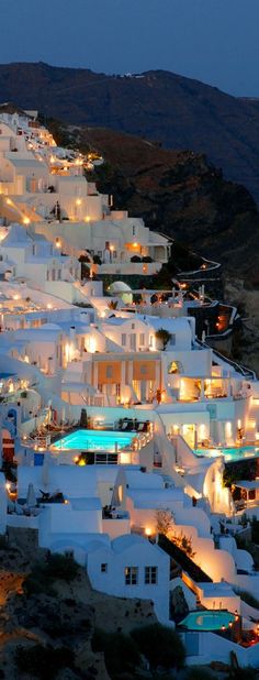 the white houses are lit up at night in the mountainside area, with lights shining on them