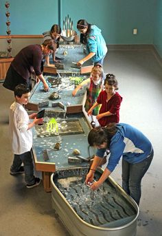 a group of people standing around a long table