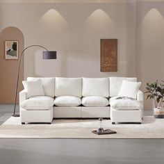 a living room with a white sectional couch and two lamps on the wall next to it