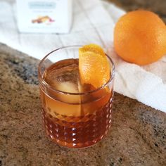 an orange sitting on top of a counter next to a glass filled with liquid and ice