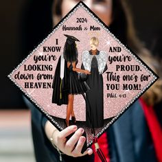 a woman holding up a graduation cap with an image of two women in black dresses