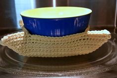 a crocheted dishcloth and blue bowl on a glass plate in the kitchen