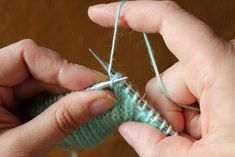 two hands are working on a knitting project