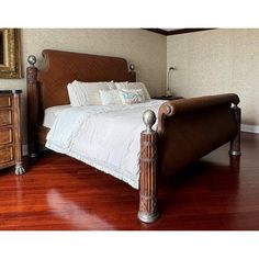 a bed sitting on top of a hard wood floor next to a dresser and mirror