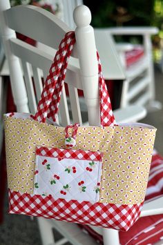 a white rocking chair with a red and white checkered bag hanging from it's back