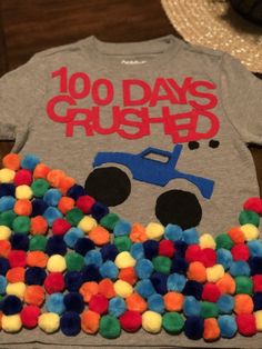 a shirt that says, 100 days crushed on it in front of a pile of pom - poms