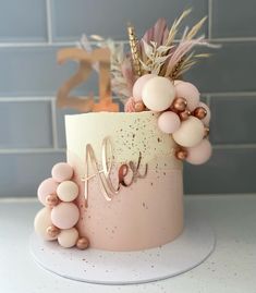 a cake decorated with pink and gold balloons