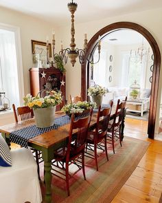 a dining room table with chairs and vases on top of it in front of an arched doorway