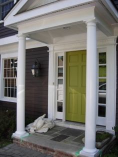 a yellow door and some white pillars in front of a house