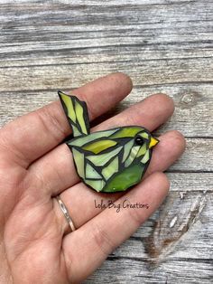 a hand holding a small stained glass bird