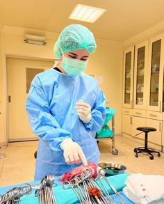 a person in scrubs and gloves standing over a table with utensils on it