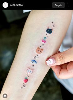 a woman's arm with tattoos on it that include cats and other small objects