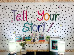 there is a polka dot wall with the words tell your story on it and two lamps