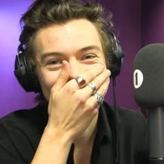 a man with headphones covering his mouth while sitting in front of a radio microphone