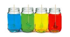 four jars filled with different colored liquids and toothpicks sticking out of them