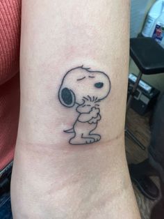 a small tattoo on the wrist of a person with a snoopy face and head