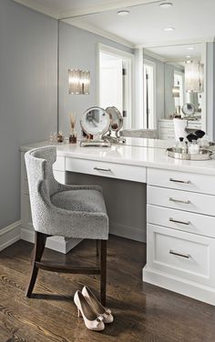 a chair sitting in front of a white desk with a mirror on top of it