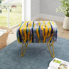 a yellow and blue blanket sitting on top of a foot stool next to a window